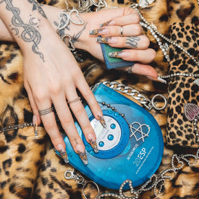 Two hands wearing our exclusive mixed animal print french tip design acrylic press-on nails while holding a CD player above a leopard faux fur background surrounded by 2000's Y2K alternative era inspired silver metal jewelry chains.