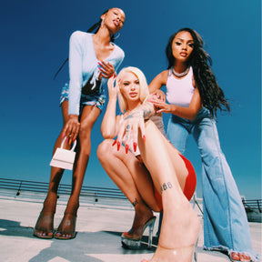 Three models wearing Y2k 2000's era styled fashion modeling Red, orange and pink leopard print with pink glitter accent nails on a downtown Los Angeles rooftop.